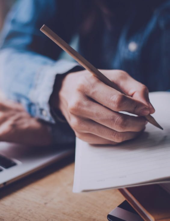 Person in blue shirt writing in notebook