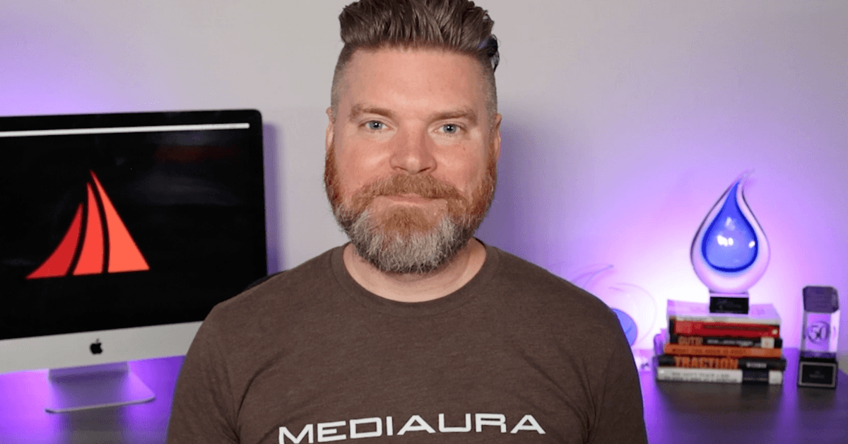Mediaura CEO Andrew Aebersold speaks in front of an office setup with awards and a computer in the background, talking about which e-commerce website is best for your business.