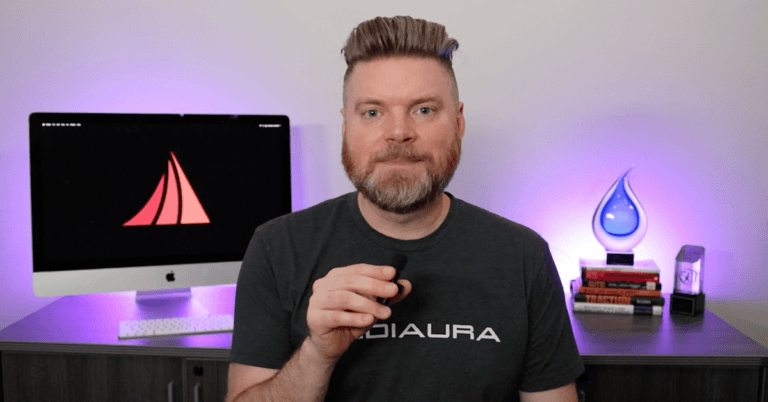 Andrew Aebersold, CEO of Mediaura, looks to camera as he explains seven mistakes you may make when building your own website. He sits in front of an office desk lir up by glowing purple lights.