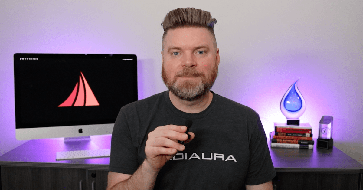 Andrew Aebersold, CEO of Mediaura, looks to camera as he explains seven mistakes you may make when building your own website. He sits in front of an office desk lir up by glowing purple lights.