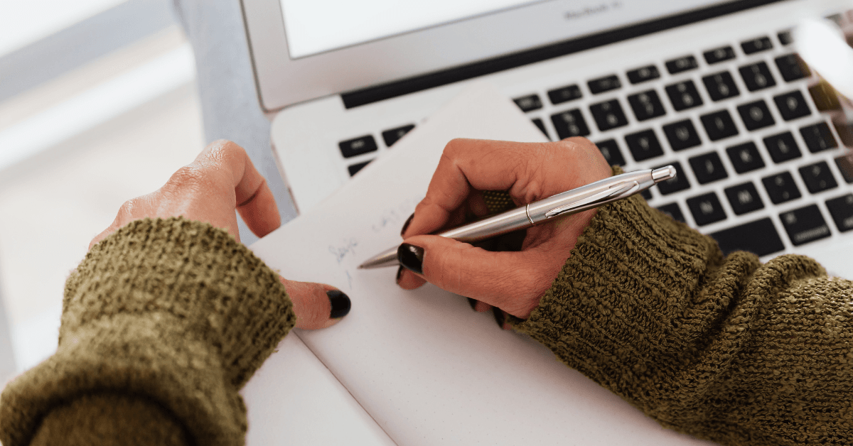 Woman strategizes on paper while she works on a laptop. Closeup of her hands writing in a notepad. A new competitor strategy is key when one emerges on the scene.