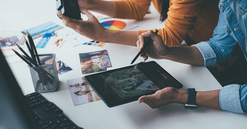 People editing photos on tablet, showing what to expect from a digital marketing agency.