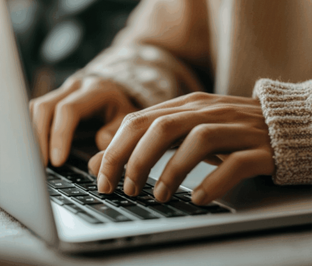 A woman typing on a laptop, thinking about the importance of SEO and AEO for marketing.